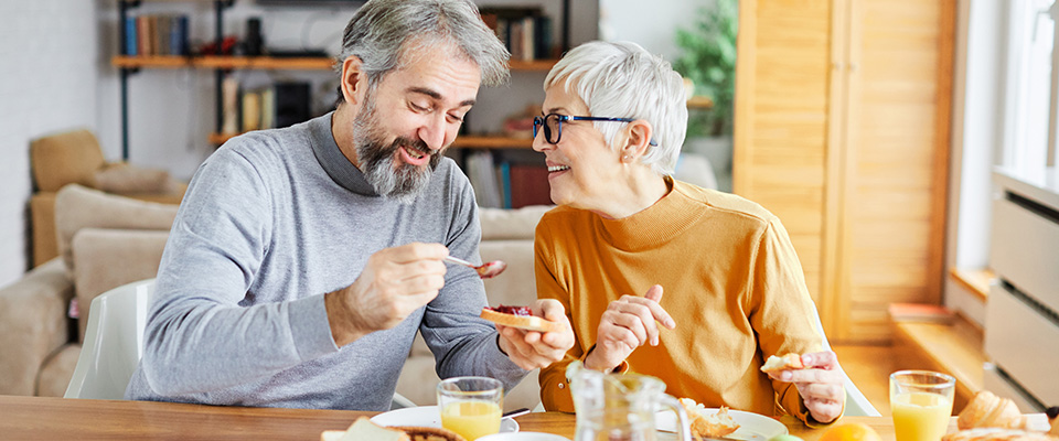 An older man and woman hugging in their kitchen.